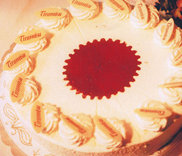 Tiramisu-Sahnetorte – Zarte Mascarponen Sahnecreme auf Wiener Böden aromatisiert mit Cafélikör. Dekoriert mit weißer Schokolade. Diese Torte enthält Alkohol.