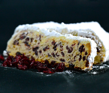 Angeschnittener Cranberry-Stollen mit einer einzelnen Scheibe und einigen Cranberries im Vordergrund